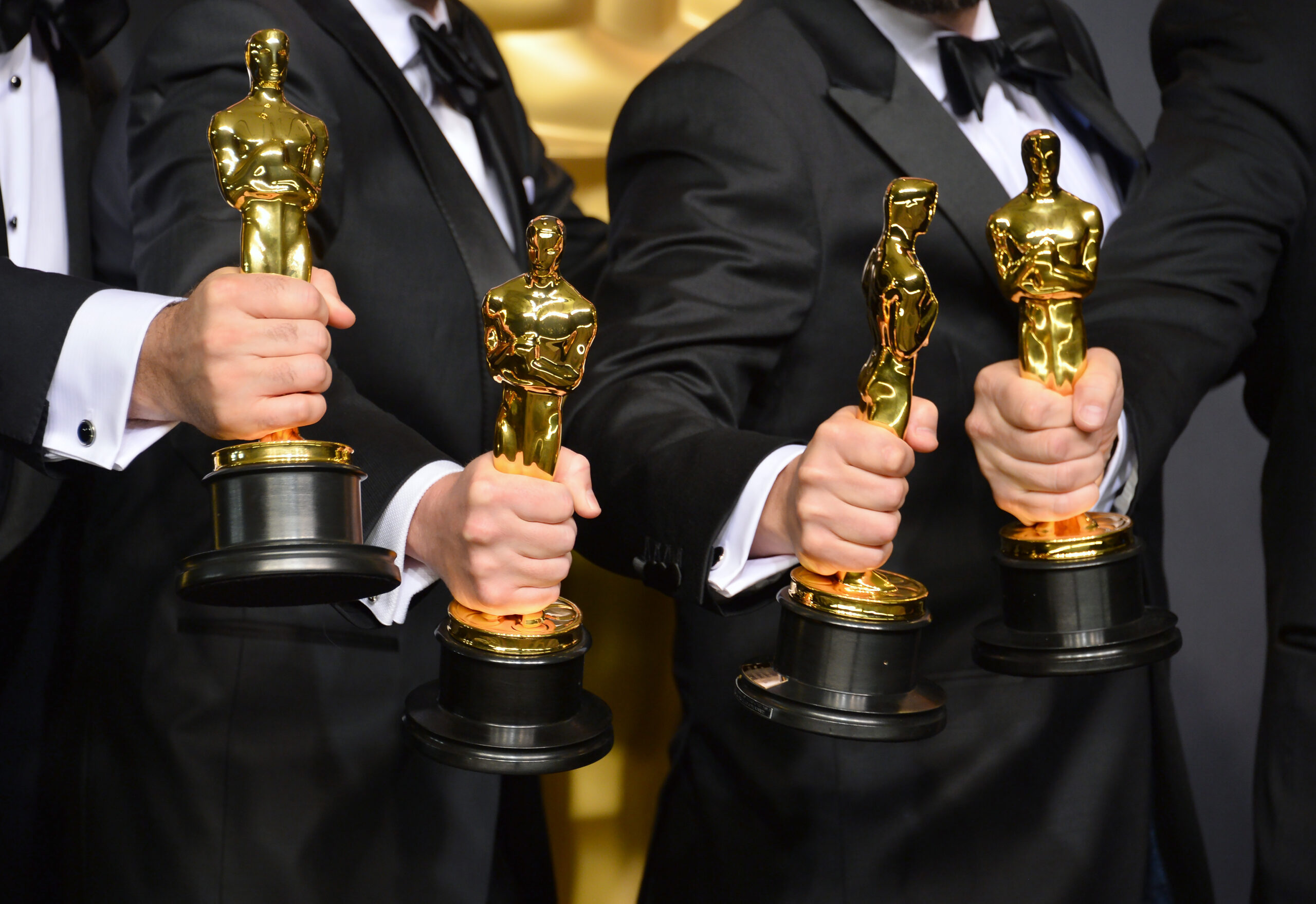 Men holding Oscars during awards season